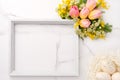 Fresh red and yellow tulips flowers bouquet, blank photo frame and eggs on white wooden background on white marble background. Spr Royalty Free Stock Photo