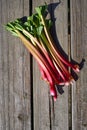 Fresh rhubarb with red stems lies in the bunch on an old wooden table