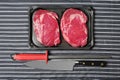 Fresh rib eye steak, Meat and food industry. Juicy premium cut of beef. Quality product on black plastic tray on black and white