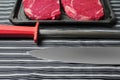 Fresh rib eye steak, Meat and food industry. Juicy premium cut of beef. Quality product on black plastic tray on black and white