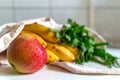 Fresh ripe apple, bunch of parsley and green onion, bananas and French baguette in canvas reusable grocery tote bag on the kitchen Royalty Free Stock Photo