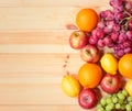 Fresh ripe apples, lemons, oranges and grape as border on wooden background