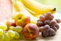 Fresh ripe apples, peaches, green and blue grapes, bananas and watermelon in basket. Healthy food on table on defocus autumn