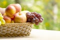 Fresh ripe apples, peaches, green and blue grapes in basket. Healthy food on table on defocus autumn background