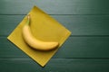 Fresh ripe banana and waxed napkin on green wooden table, top view. Space for text