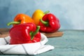 Fresh ripe bell peppers on wooden table against light blue background, space for