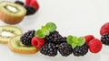 Fresh ripe blackberries, raspberries and kiwi slices with mint leaves scattered on a glass table Royalty Free Stock Photo