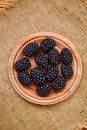 Fresh ripe blackberries in wooden plate on rustic table, top view Royalty Free Stock Photo