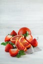 Fresh ripe blood oranges and strawberries, slices, rustic food photography on white wood plate