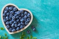 Fresh ripe blueberries in heart shaped bowl on blue background Royalty Free Stock Photo