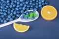 Fresh and ripe blueberries in a wooden spoon. A heap of organic berries and juicy citrus on a dark blue background. Royalty Free Stock Photo