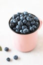 Fresh ripe blueberry in mug on white table.