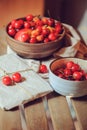 Fresh ripe cherries on plate with wrapped gift on wooden table