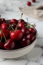 Fresh ripe cherries with water drops in bowl on white marble table, closeup Royalty Free Stock Photo