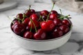 Fresh ripe cherries with water drops in bowl on white marble table, closeup Royalty Free Stock Photo