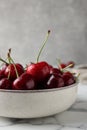 Fresh ripe cherries with water drops in bowl on white marble table, closeup Royalty Free Stock Photo