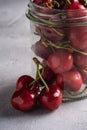 Fresh ripe cherry branch near to cherries with green leaves in glass jar, summer vitamin berries on grey stone background Royalty Free Stock Photo