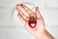 A fresh, ripe cherry in the shape of a heart in the hands of a girl, against the background of a white plate. The Royalty Free Stock Photo