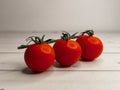 Fresh ripe cherry tomatoes on a green branch on a background of light wooden boards