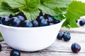 Fresh ripe currant berries in a white bowl on wooden background near green leaves. Juicy fruits currant. Black currant Royalty Free Stock Photo