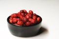 Fresh ripe dark red wild strawberries in a black bowl on a white background Royalty Free Stock Photo