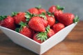 Ripe strawberry in a white bowl on brown wooden table, selective focus Royalty Free Stock Photo