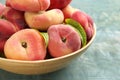 Fresh ripe donut peaches in bowl on light blue wooden table, closeup Royalty Free Stock Photo