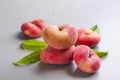 Fresh ripe donut peaches with leaves on light table, closeup Royalty Free Stock Photo