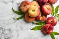 Fresh ripe donut peaches with leaves on white marble table, flat lay. Space for text Royalty Free Stock Photo