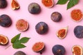 Fresh ripe figs with green leaves on pink background, flat lay Royalty Free Stock Photo