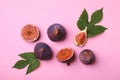 Fresh ripe figs with green leaves on pink background, flat lay Royalty Free Stock Photo