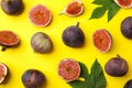 Fresh ripe figs with green leaves on yellow background, flat lay Royalty Free Stock Photo