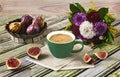 Fresh ripe figs on vintage plate, green cup of coffee, bouquet of burgundy dahlias, purple shawl as decor.