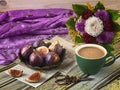 Fresh ripe figs on vintage plate, green cup of coffee, bouquet of burgundy dahlias, vintage scissors and purple shawl as decor.