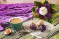 Fresh ripe figs on vintage plate, green cup of coffee, bouquet of burgundy dahlias, vintage scissors and purple shawl as decor.