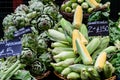 Fresh ripe fresh organic globe artichokes and yellow sweet corn displayed for sale at a street food market, side view of healthy v Royalty Free Stock Photo