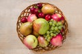 Fresh ripe fruit - apples, pears, grapes and plums in a wicker wooden plate on a wooden table. Top view. Autumn harvest of fruits Royalty Free Stock Photo