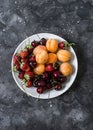 Fresh ripe fruit - apricots, cherries, strawberries on a dark background, top view Royalty Free Stock Photo