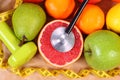 Fresh ripe fruits, tape measure, stethoscope and dumbbells for fitness, healthy lifestyles concept Royalty Free Stock Photo