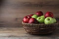 Fresh ripe green and red apples with water drops in wicker bowl on wooden table, space for text Royalty Free Stock Photo