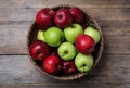 Fresh ripe green and red apples with water drops in wicker bowl on wooden table, top view Royalty Free Stock Photo