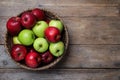 Fresh ripe green and red apples with water drops in wicker bowl on wooden table, top view. Space for text Royalty Free Stock Photo