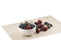 Fresh ripe honeysuckle berries and cherry in a ceramic bowl on a wooden board. Healthy breakfast. White bowl of honeysuckle. Royalty Free Stock Photo