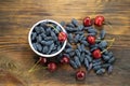 Fresh ripe honeysuckle berries and cherry in a ceramic bowl on a wooden board. Healthy breakfast. White bowl of honeysuckle. Royalty Free Stock Photo