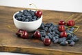 Fresh ripe honeysuckle berries and cherry in a ceramic bowl on a wooden board. Healthy breakfast. White bowl of honeysuckle. Royalty Free Stock Photo