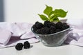 Fresh ripe juicy blackberries in a plate on a white background. Ripe blackberries with leaves in a transparent bowl. Royalty Free Stock Photo