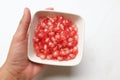fresh ripe juicy grains Pomegranate, (Punica granatum) seeds in the bowl white square in hand woman