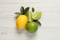 Fresh ripe lemon, limes and green leaves on white wooden background, flat lay Royalty Free Stock Photo