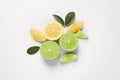 Fresh ripe lemons, limes and green leaves on white background, top view Royalty Free Stock Photo