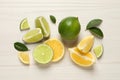 Fresh ripe lemons, limes and green leaves on white wooden background, flat lay Royalty Free Stock Photo